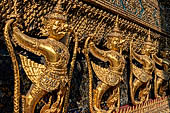 Bangkok Grand Palace,  Wat Phra Keow (temple of the Emerald Buddha). Golden garudas holding nagas support the external wall of the ubosot. 